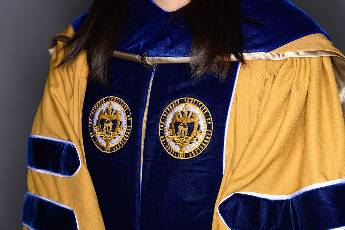 Closeup of Georgia Tech Ph.D. regalia in gold and navy blue with the seal of the Institute on the lapels.
