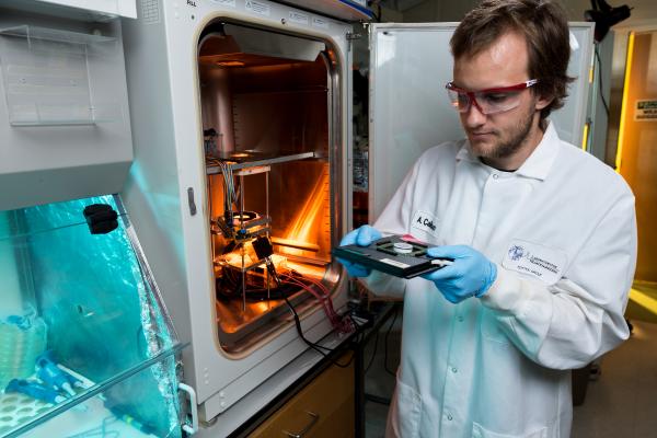 Riley Zeller-Townson, a Georgia Tech Ph.D. student in Steve Potter’s lab, demonstrates preparation of a cell culture for placement into the optoclamp. The optoclamp uses a computer to acquire and process the neuronal response to optical stimuli in real-time and then vary the light input to maintain a desired firing rate. (Credit: Rob Felt, Georgia Tech)