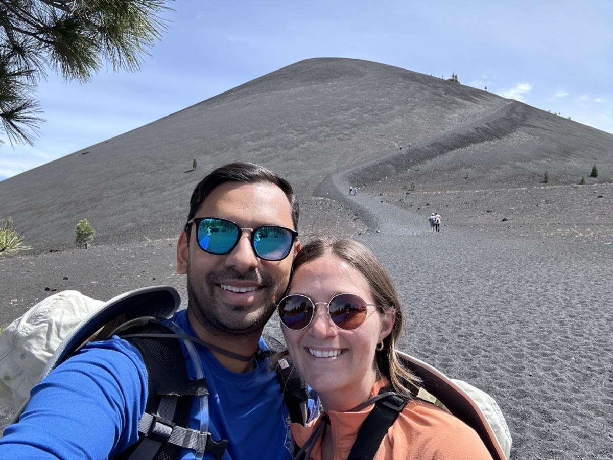 Photo of couple Tushar (on the left) and his wife Mattie (on the right) standing in front of a sand dune